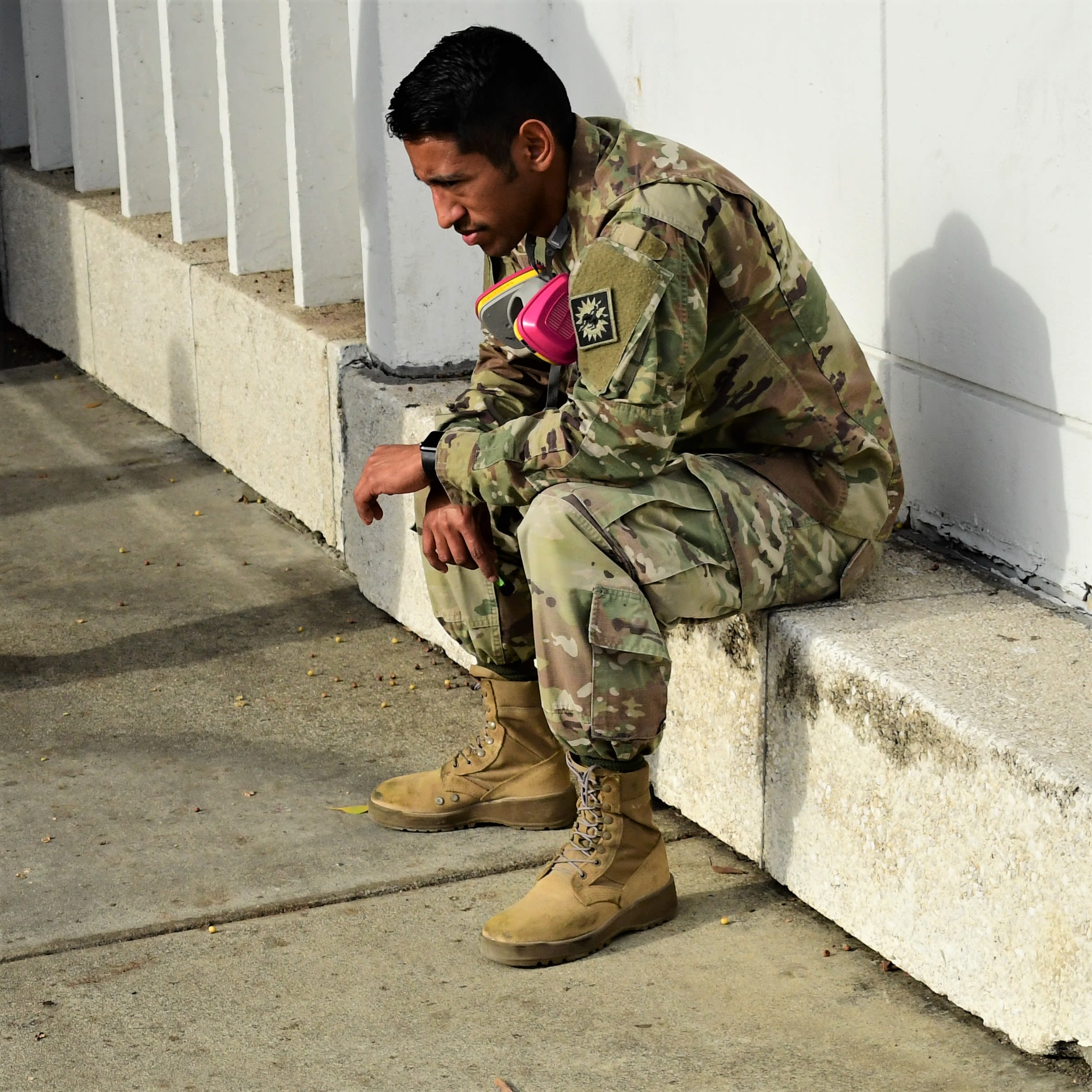A Soldier sits on a cement bench taking a break.