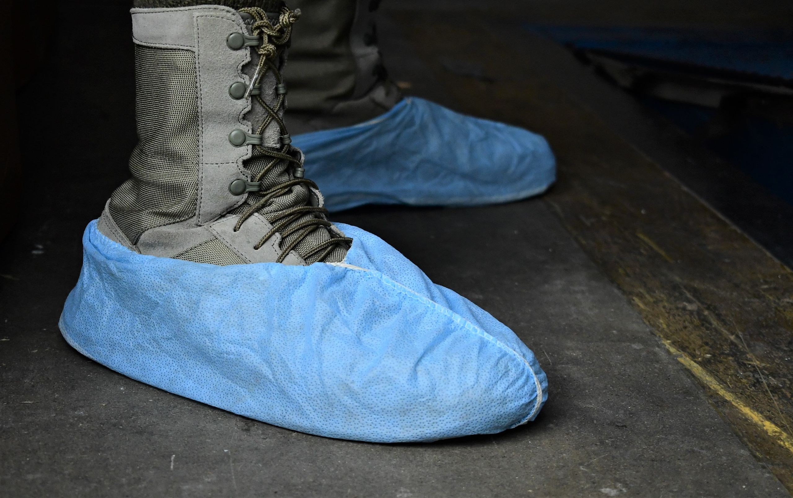 Blue disposable shoe covers a pair of combat boots.