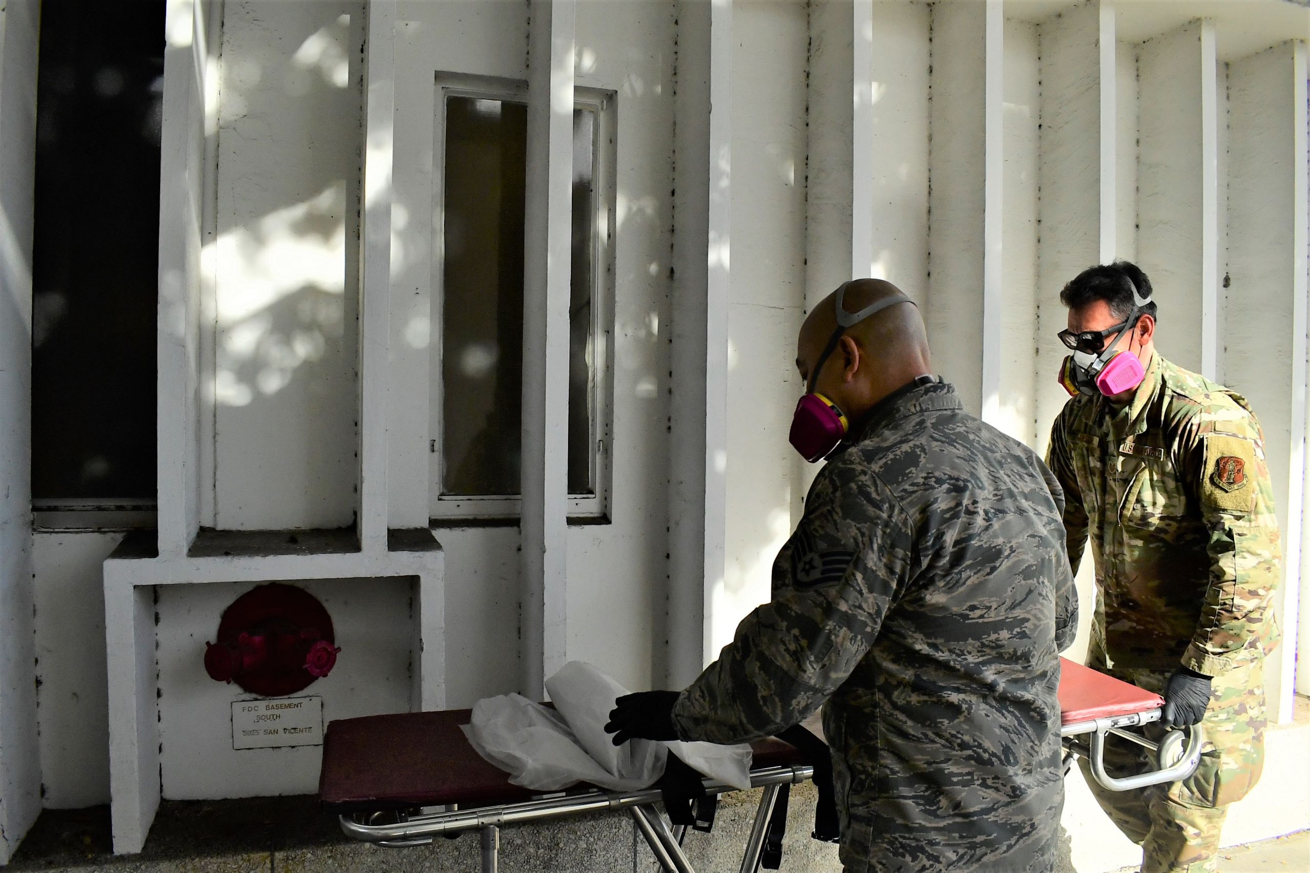 Airmen roll a stretcher to a rear exit of a local hospital.