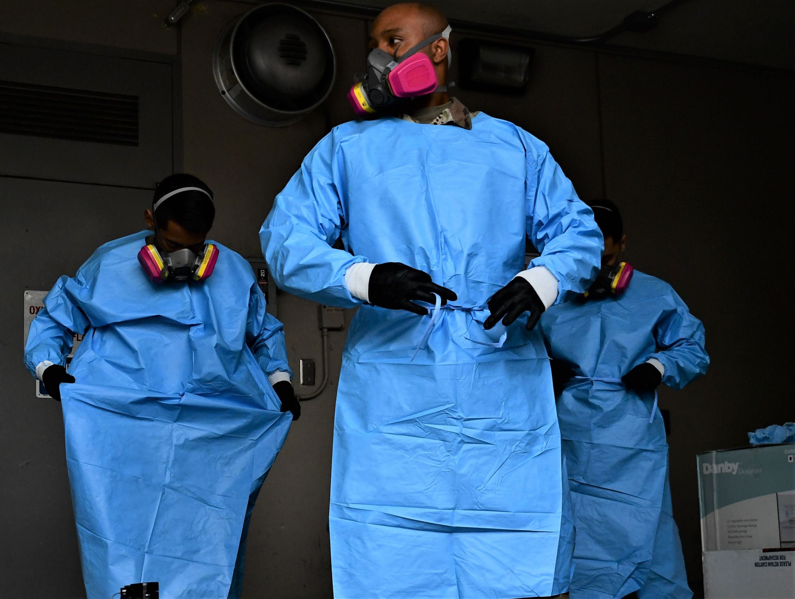 Servicemembers dawn blue disposable gowns, gloves, and masks.