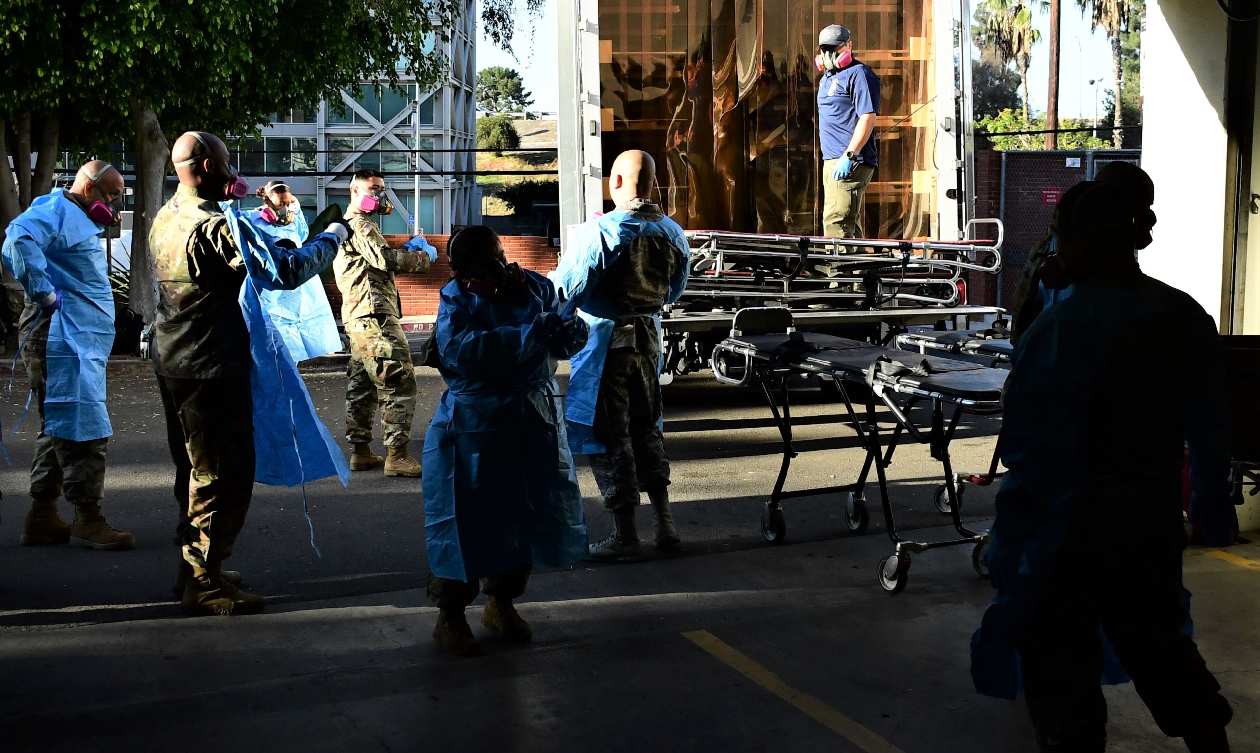 A group of airman and soldiers dawn disposable gowns, gloves, and face masks
