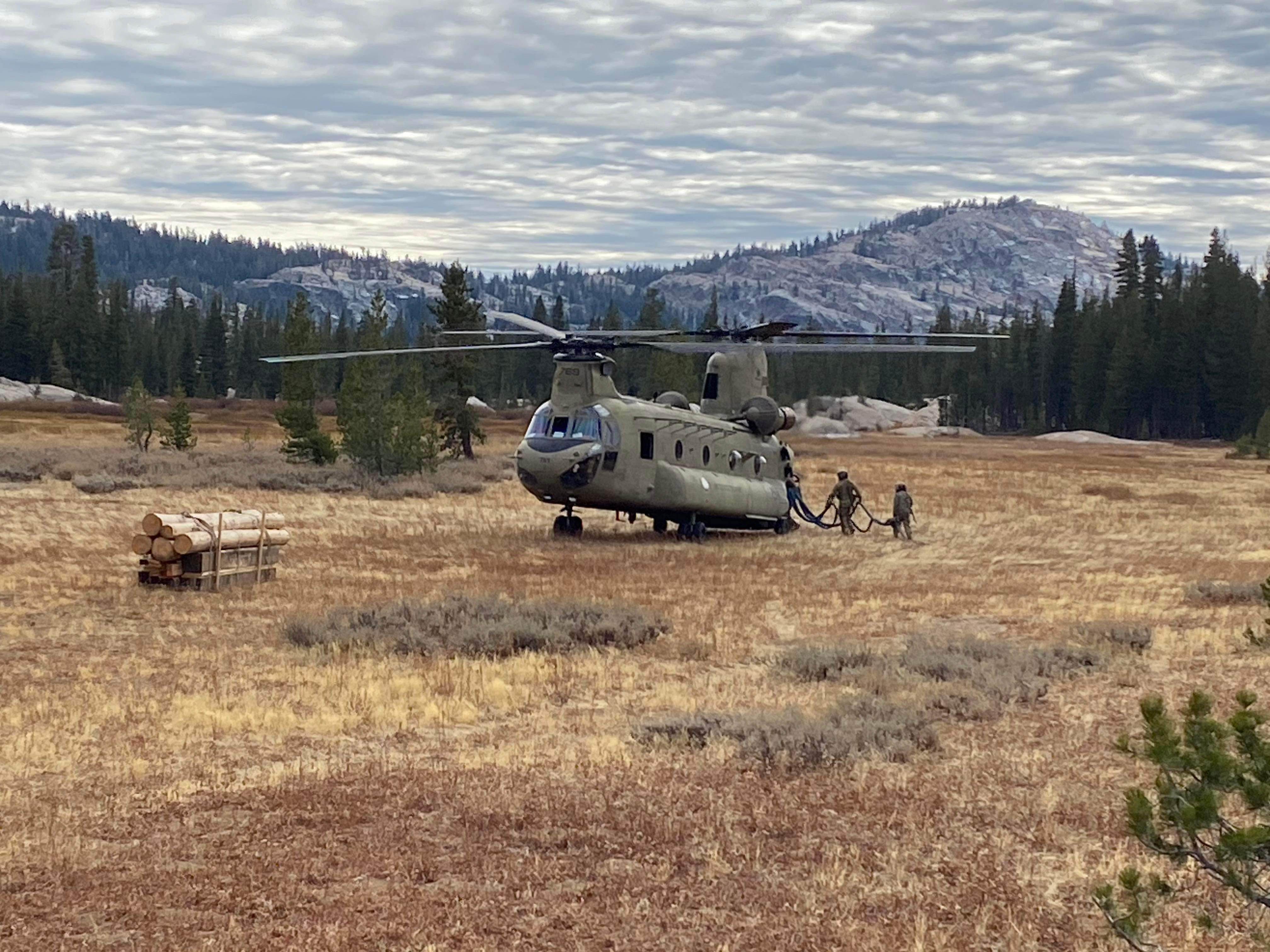 A CH-47 Chinook in a field with mountains in the background