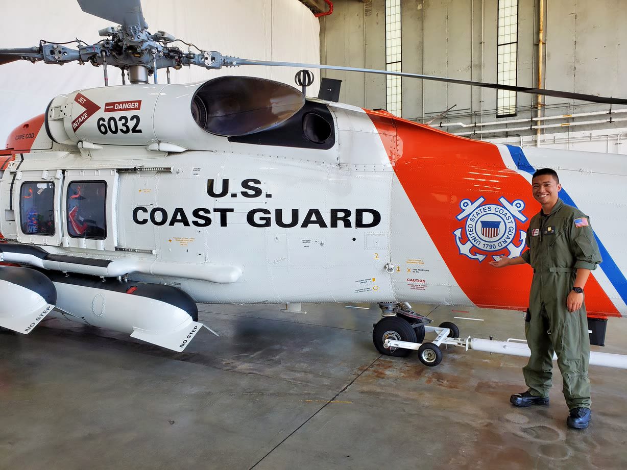 Coast Guard Cadet stands next to helicopter.