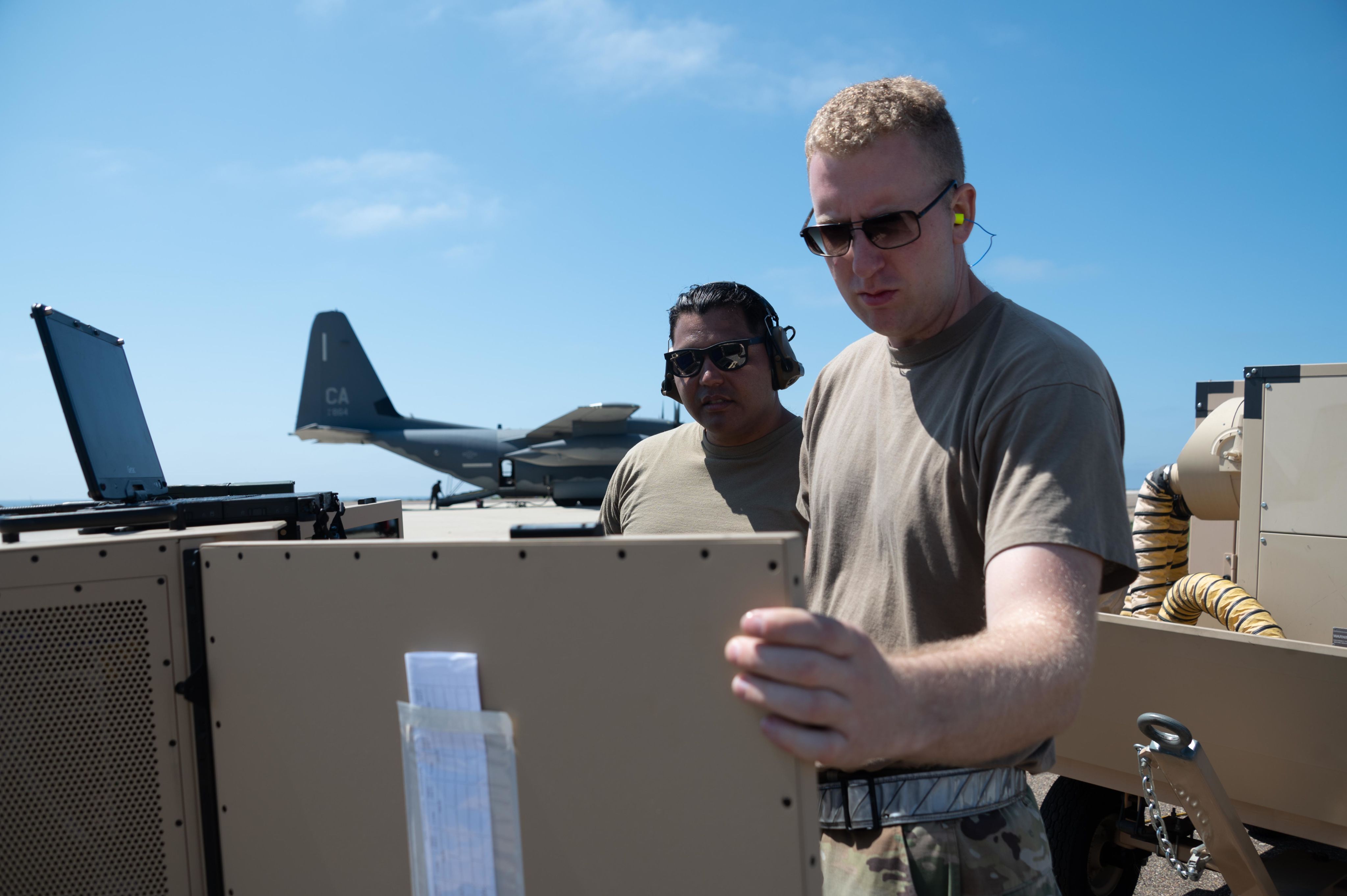 Two Airmen stand in front of computer