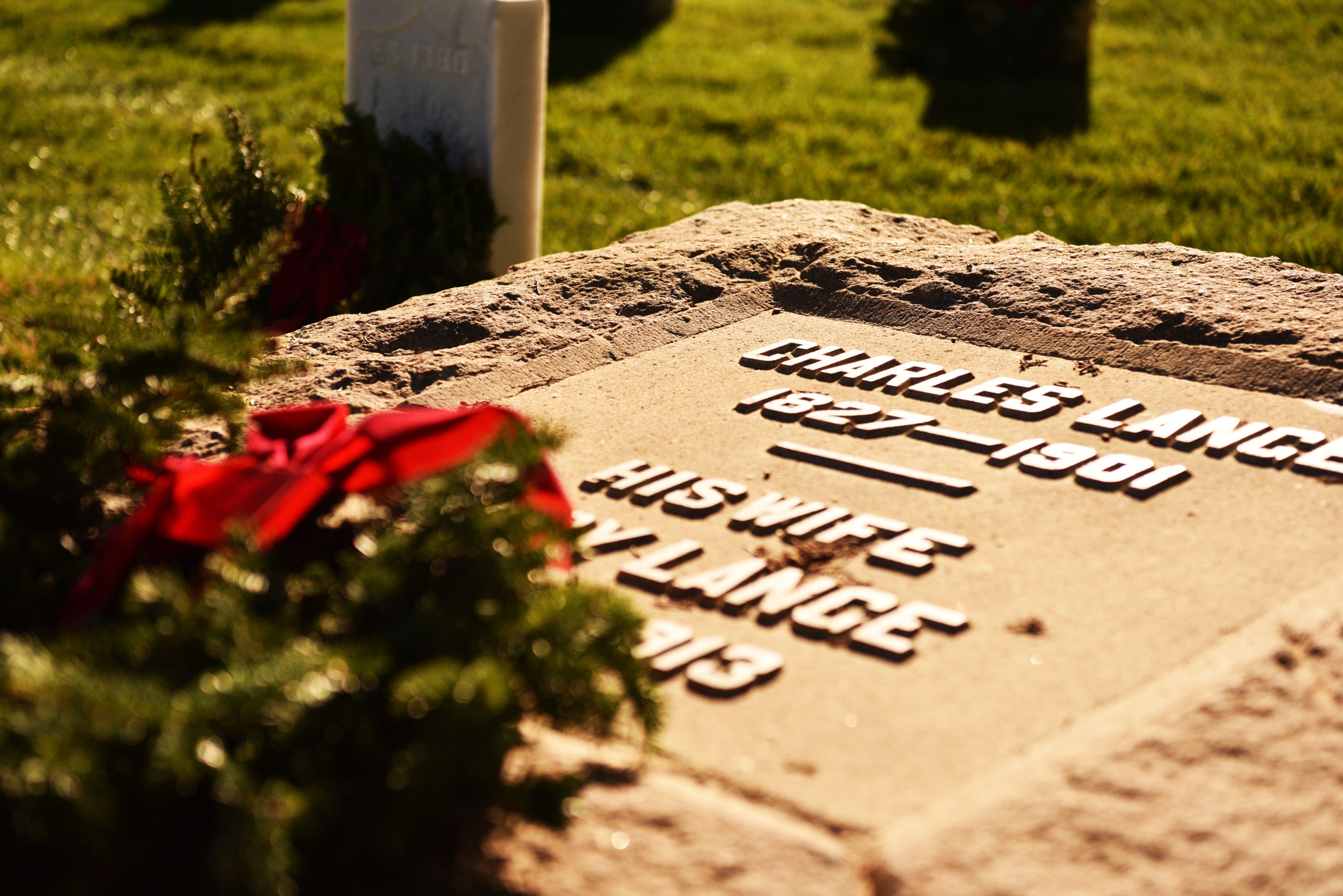 A wreath lays on top of a Soldiers grave. 