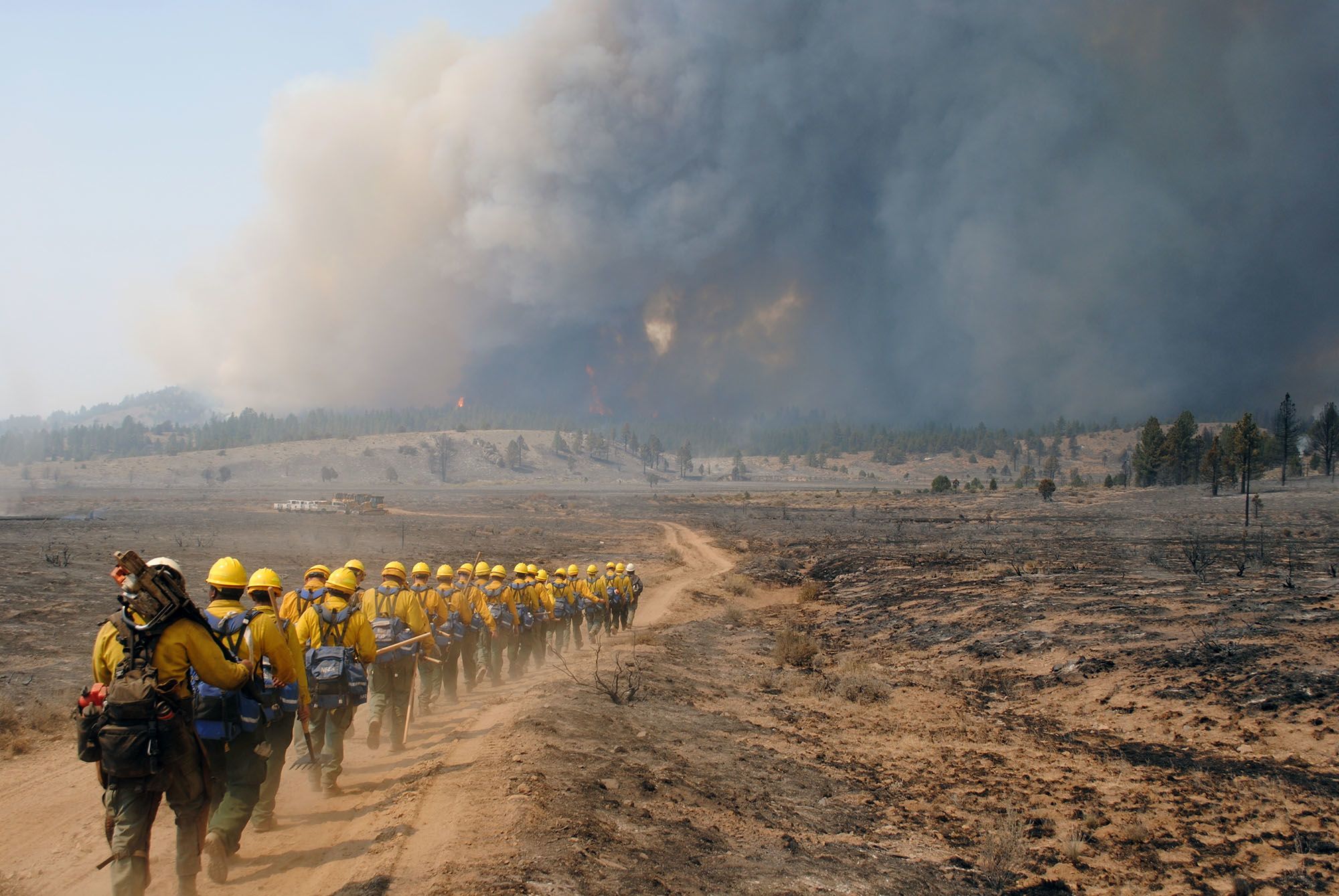 Firefighting crew on trail heading toward smoke.