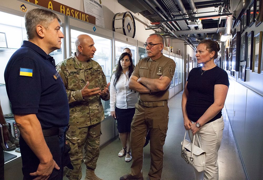 Five people talk in hallway.