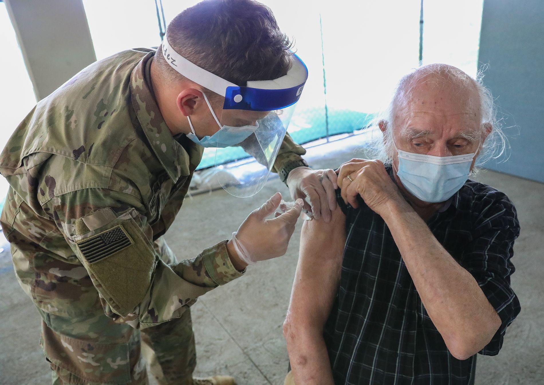 Soldier vaccinates elderly man.