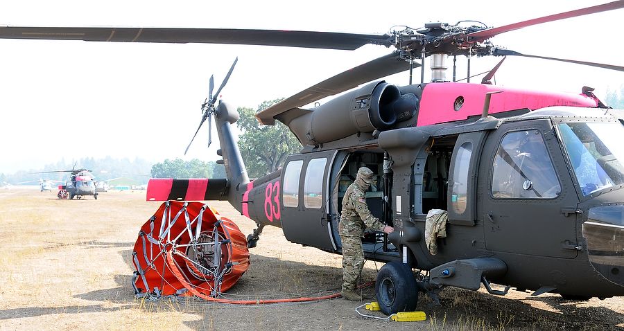Black Hawk helicopter with water bucket attached.
