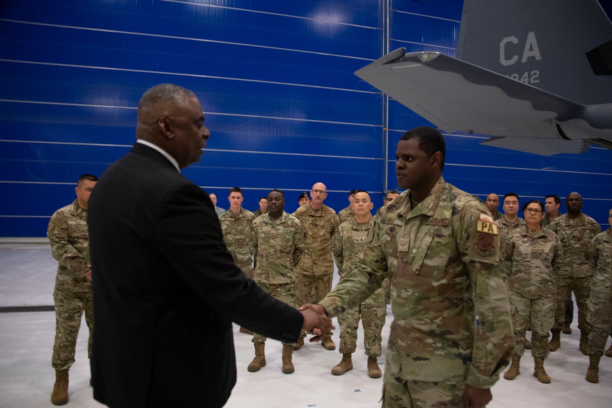 Man presents coin to Airman.