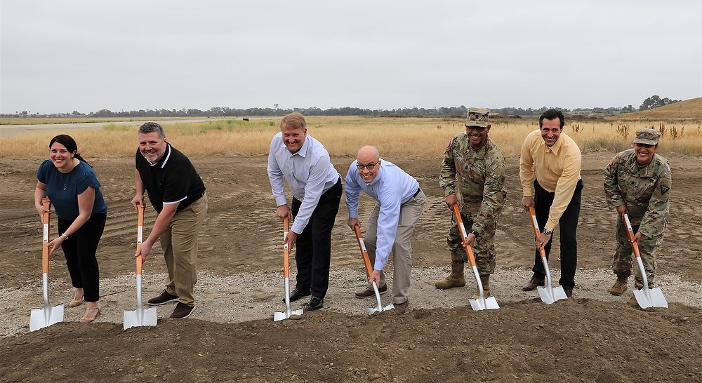 Seven people with shovels in dirt.