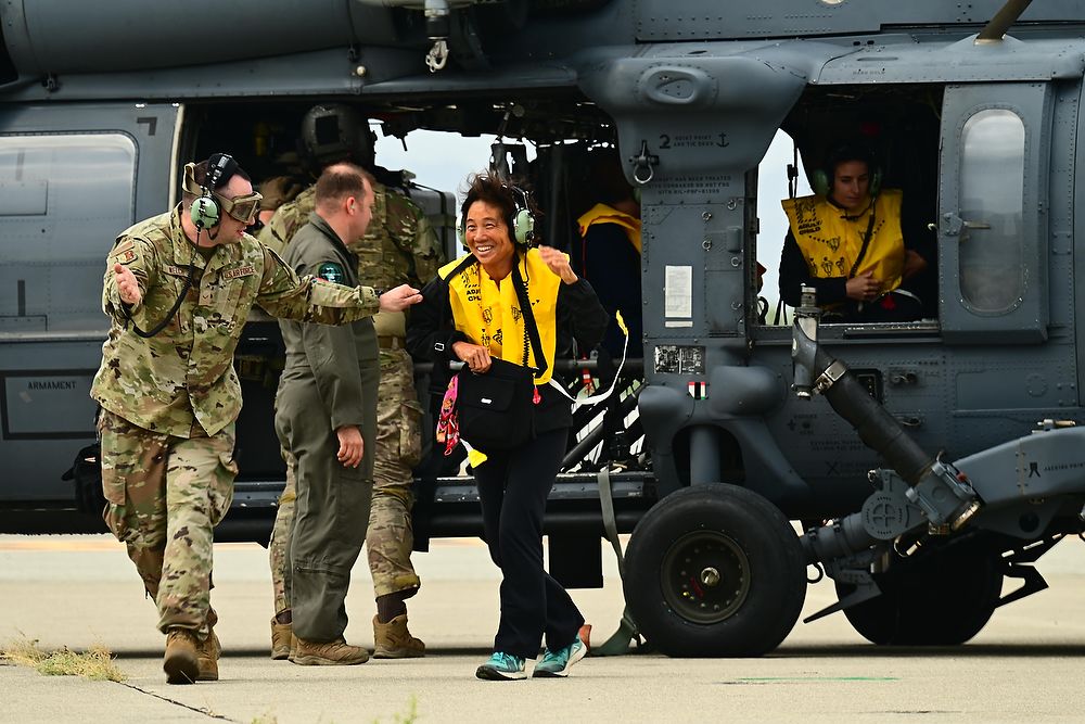 Airman escorts woman off helicopter.