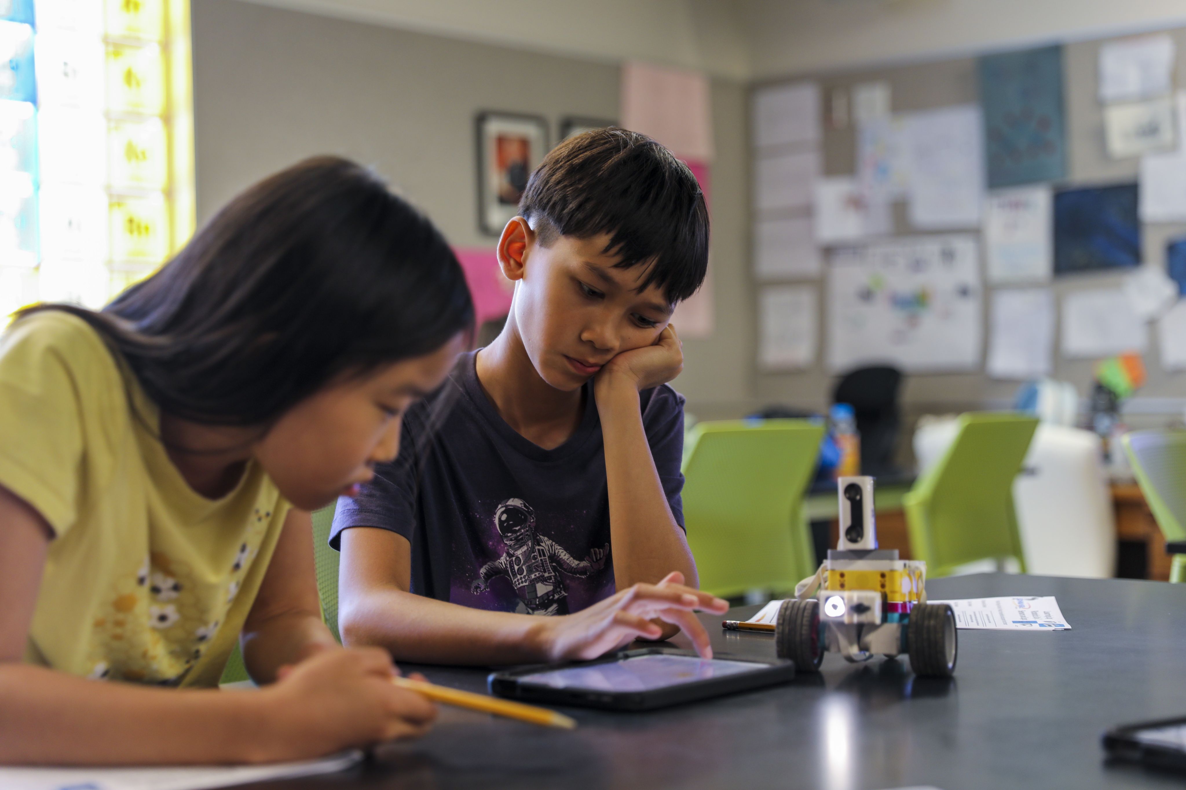 Two children sit together while looking at an Ipad