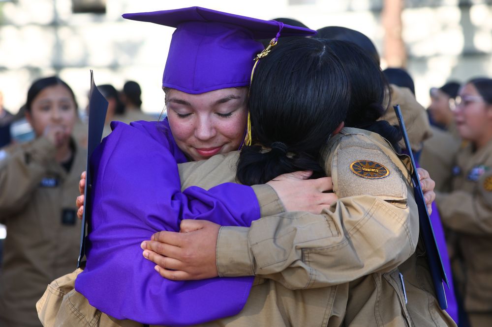 Graduate hugs military staff member.