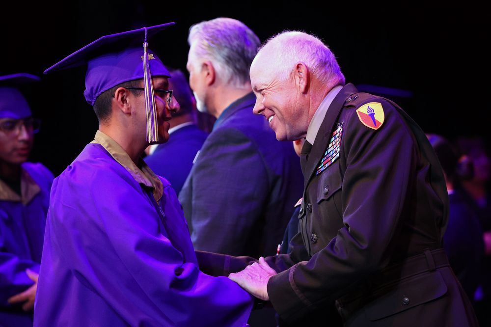 General officer congratulates high school graduate at military school.