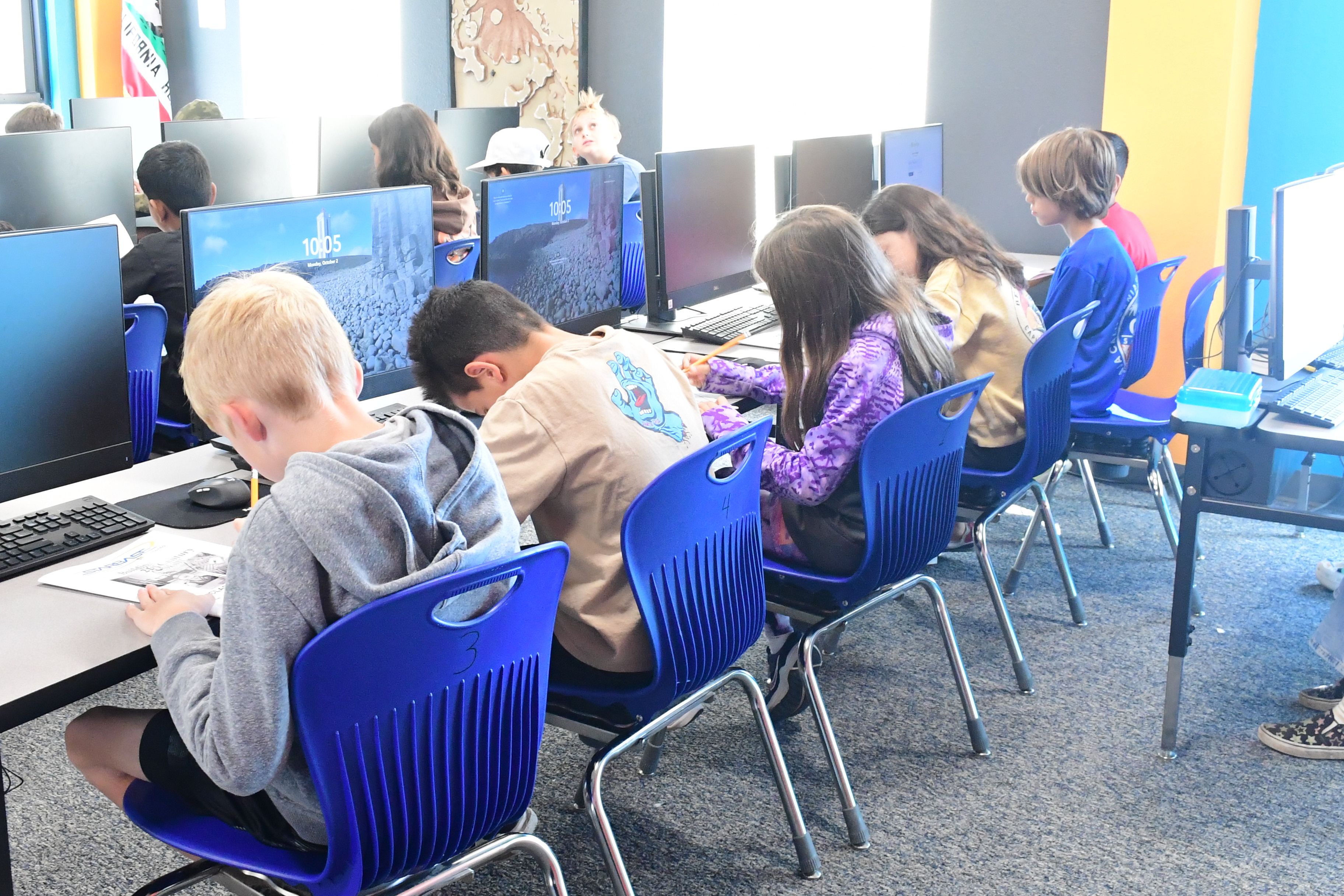 Children sit at desks and write