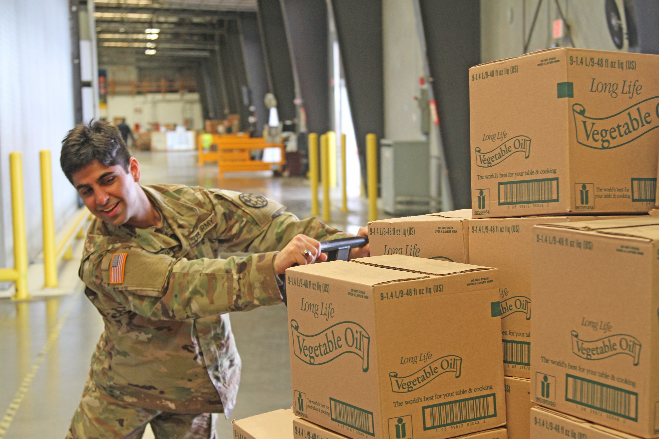 Soldier pushes cart full of boxes.