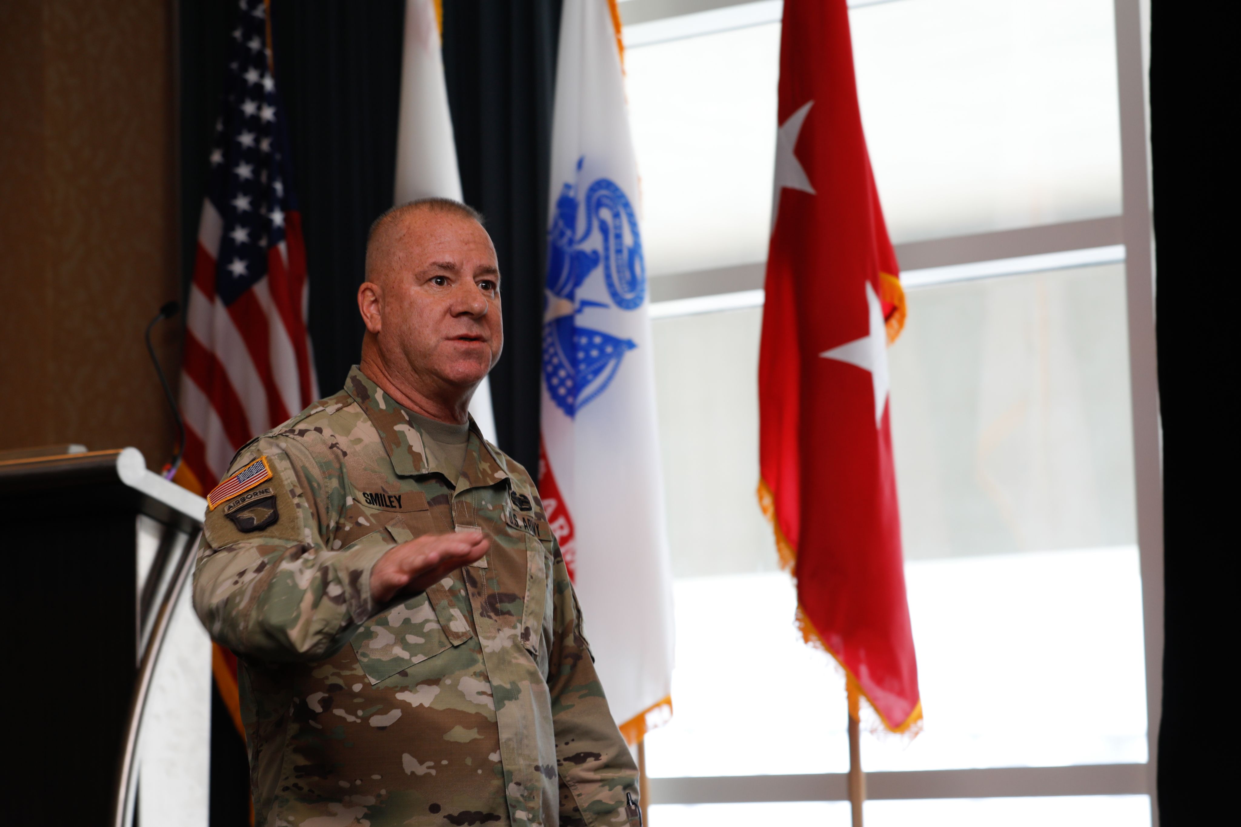 Soldier speaks in front of flags