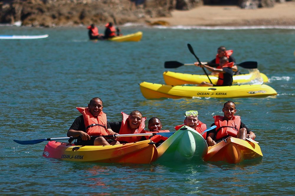 Teens in kayaks on water.