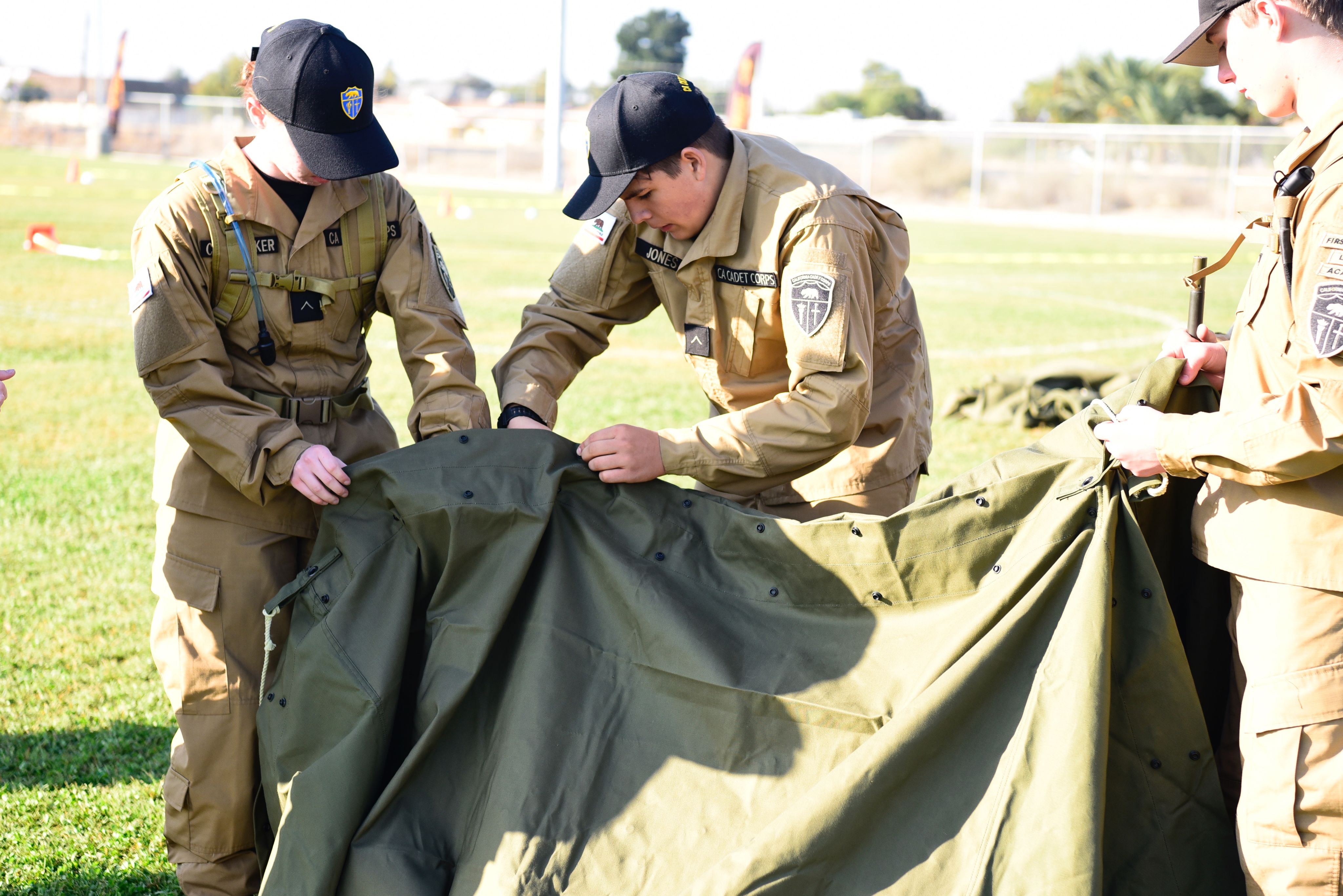 3 cadets build a tent.