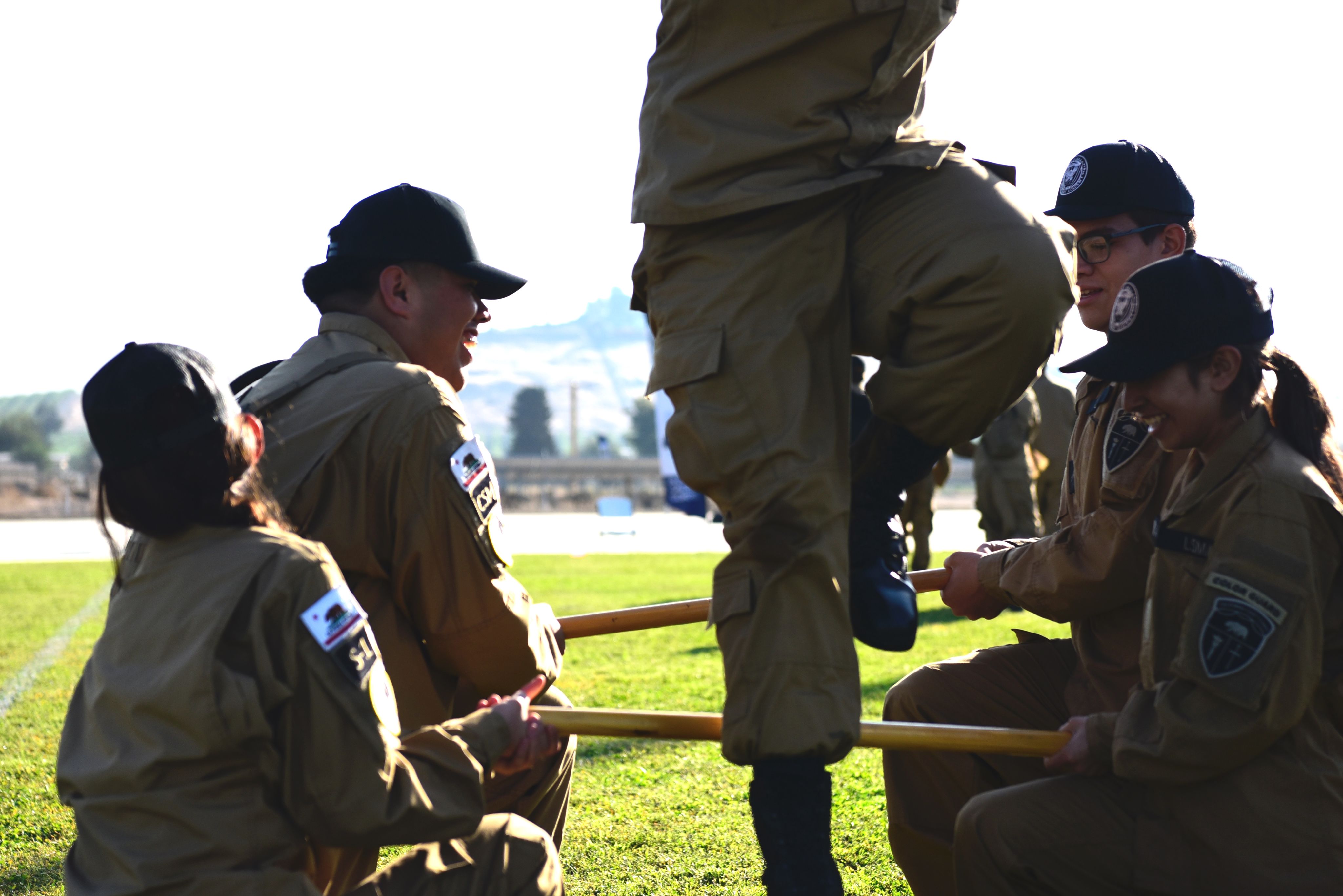 A group of cadets kneel while a team member jumps over them.